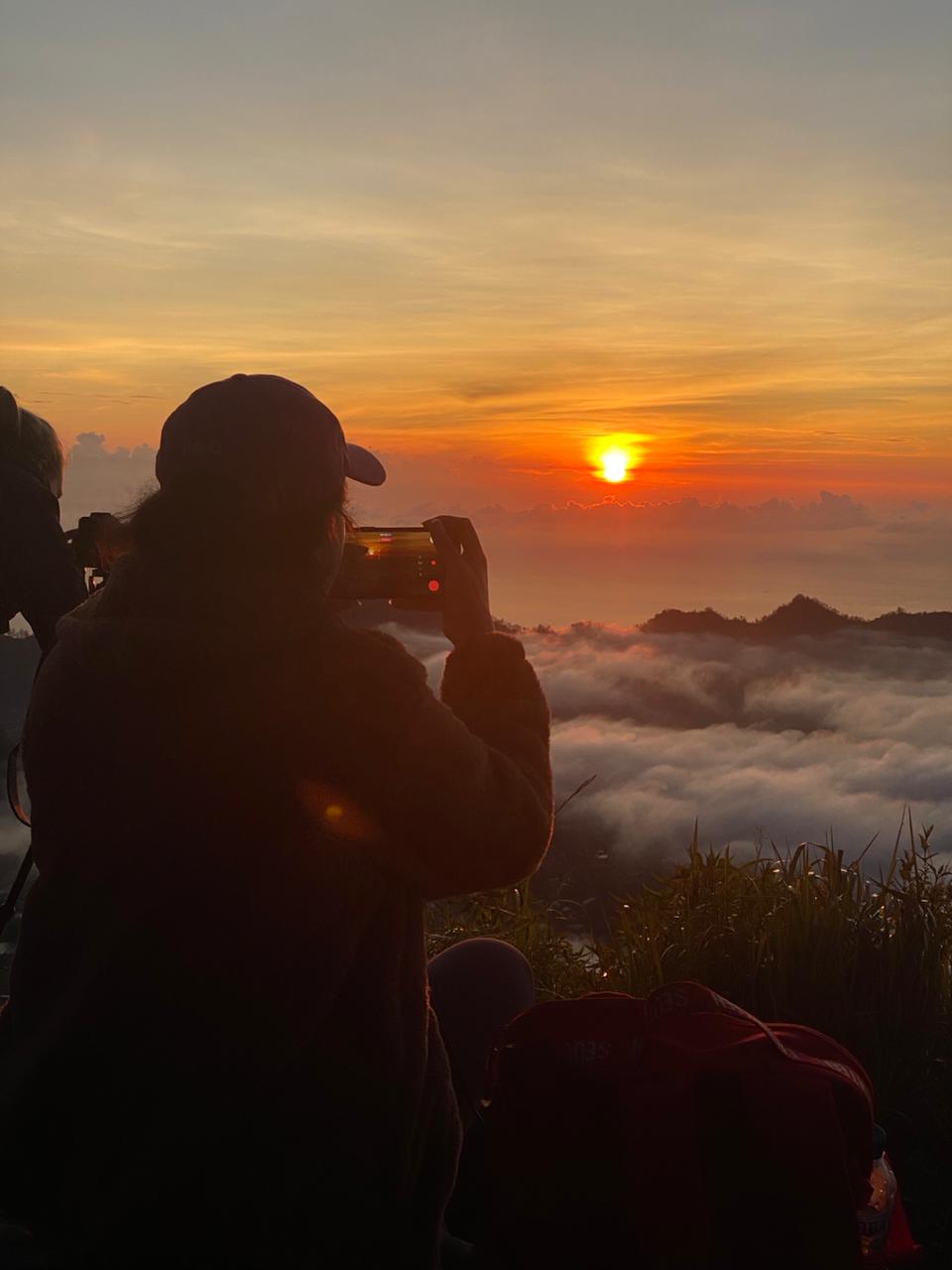 Traveler photographing sunrise on Mount Batur